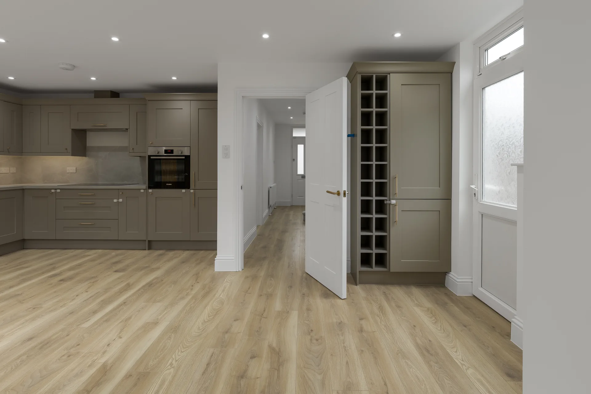 Wide View Of A Modern Kitchen And Hallway Featuring Built In Wine Storage And Neutral Toned Cabinetry.